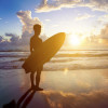 surfer man standing on beach and holding a surfboard