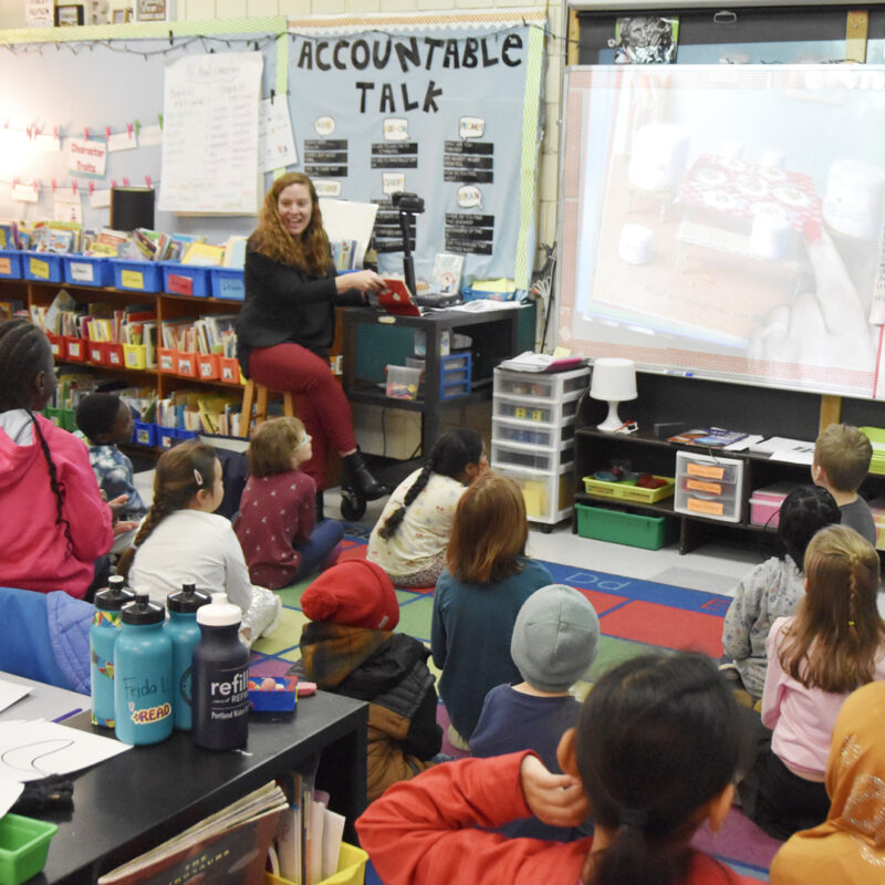Kelsey Marquis, the Executive Vice President & CFO of cPort, a Portland credit union, reads to a class at Talbot Community School in Portland, Maine.