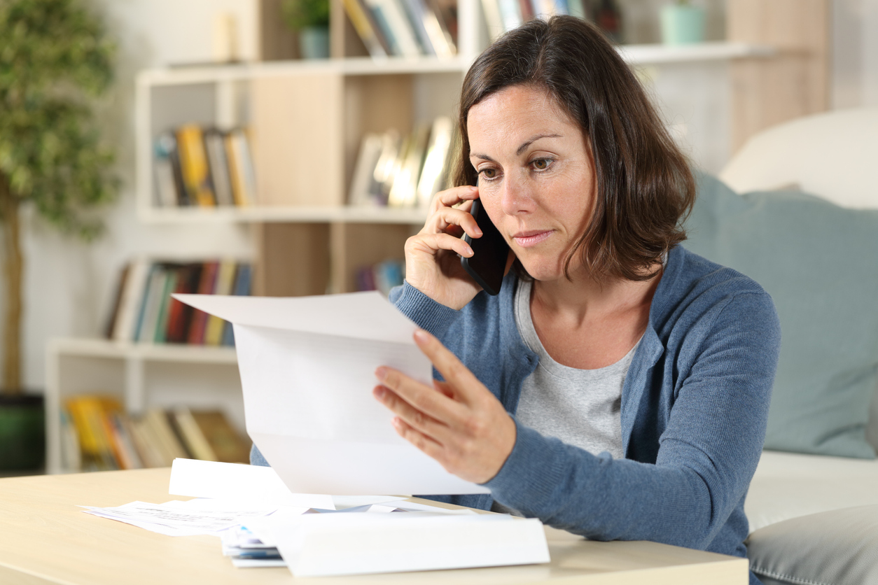 woman checking bank statement and calling cPort Member Care on phone because suspicious fraus and scams activity