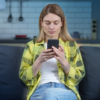 Woman sitting on a couch in her home using a mobile device to protect herself from cyber threats