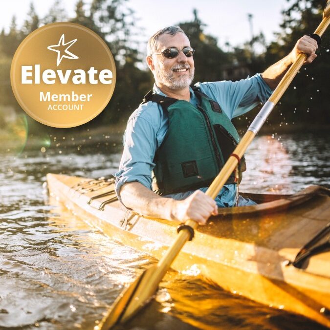 A mature adult man glides through the cool waters of Gig Harbor, Washington, a small bay in the Puget sound, paddling in a classic wood kayak. The evening sun shines from behind, a smile on the mans face as he takes in the beauty of the great outdoors. Horizontal image with copy space.