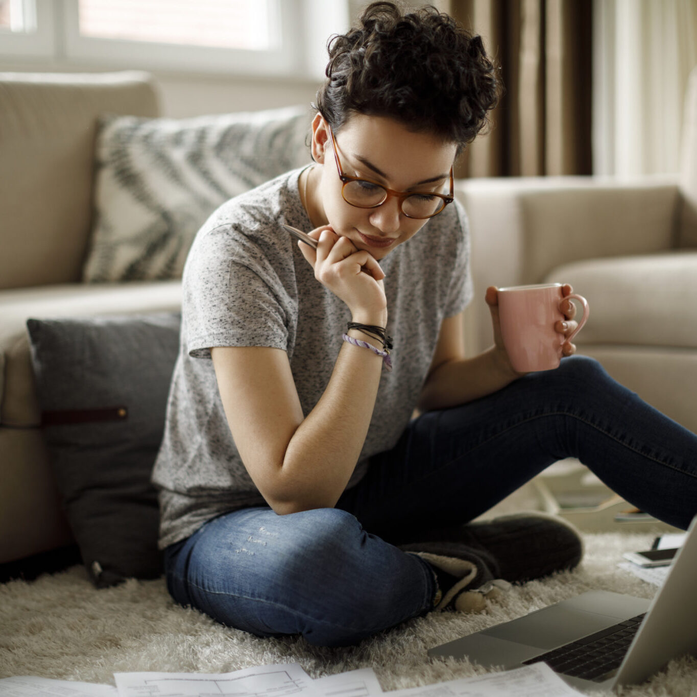 Young Woman Working At Home person sitting on the floor with a cup of coffee or tea