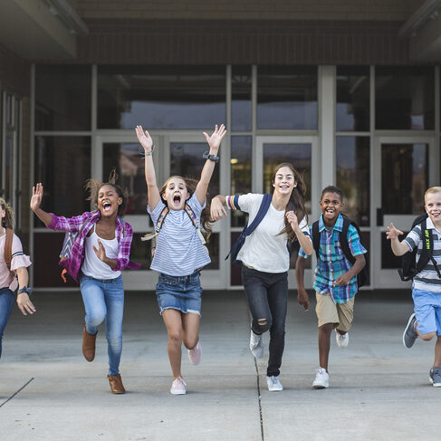 Group school school kids running as they leave the school building Back to school photo of a diverse group of children wearing backpacks and ready to go home from school