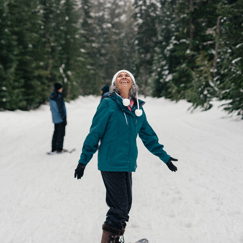 Older woman looking up at the snowfall